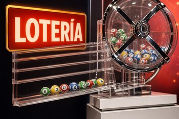 Un bombo transparente con esferas numeradas junto a una bandeja acrílica con bolas organizadas y un cartel rojo con la palabra LOTERÍA.