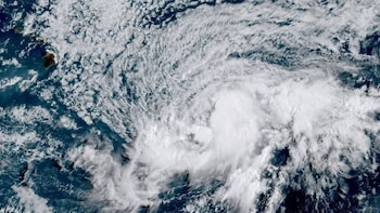 Vista aérea del océano con nubes blancas que forman un patrón en espiral, y dos islas visibles en la parte superior izquierda de la imagen