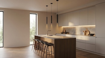 Vista amplia de una cocina moderna con una isla central de madera clara y seis taburetes negros, gabinetes grises, salpicadero de mármol y dos ventanales grandes.