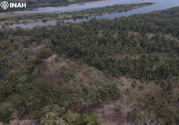 Vista aérea de un paisaje con un río, islas de tierra, densos árboles, palmeras, vegetación arbustiva y áreas de tierra seca. Logotipo de INAH