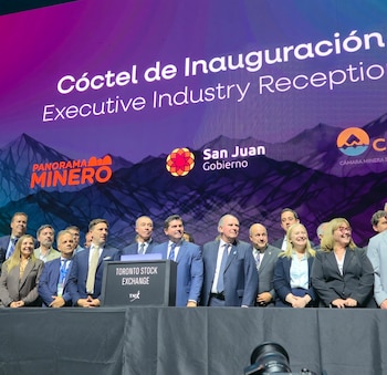 Un grupo de ejecutivos y funcionarios en un escenario. Detrás, una pantalla muestra "Cóctel de Inauguración" y logos. Un podio con "Toronto Stock Exchange" está visible