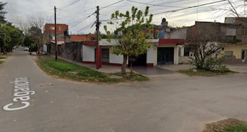 Vista de una calle con el nombre Cagancha, casas residenciales, árboles, césped y postes de servicios públicos bajo un cielo nublado