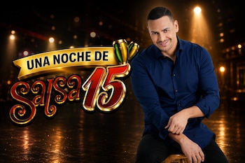 Un hombre sonriente de camisa azul sentado. Un logotipo con texto "Una Noche de Salsa 15" y dos congas. Fondo oscuro con luces brillantes