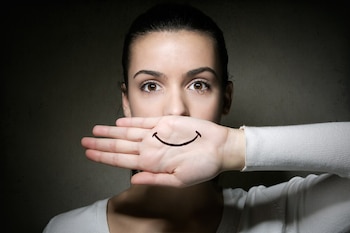 Mujer joven llora mientras cubre su boca con una sonrisa (Freepik)