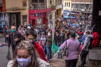 Peatones con tapabocas pasean frente