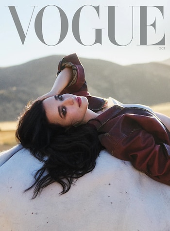 Mikey Madison recostada sobre un caballo blanco en un entorno natural bajo el logotipo de la revista Vogue