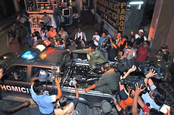 Vista aérea de multitud de periodistas con cámaras alrededor de camioneta policial de Homicidios con balizas y un cuerpo cubierto en la caja
