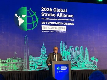 Hombre en traje habla en un podio. Detrás, una pantalla azul con el logo de la Alianza Global contra el Accidente Cerebrovascular 2026 y un skyline estilizado de Buenos Aires