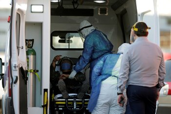 Un migrante con sospecha de padecer COVID-19 es ayudado por personal de salud para ser trasladado desde Casa INDI a un hospital en Monterrey, Foto: (REUTERS/Daniel Becerril)