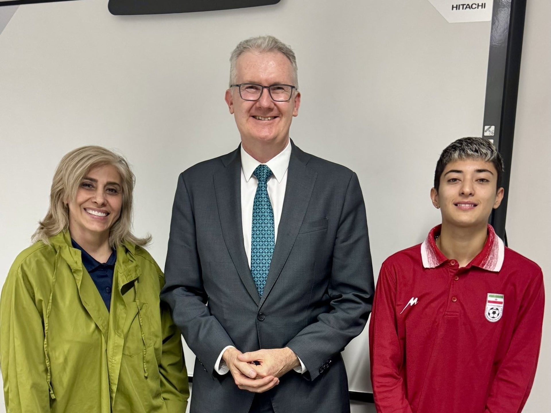 El ministro de Interior australiano, Tony Burke, junto a Zahra Soltan Meshkeh Kar, integrante del personal de apoyo de la selección fenemina de Irán de fútbol, a su derecha, y la futbolista Mohadeseh Zolfi, a su izquierda