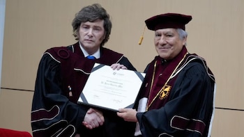 Javier Milei y un hombre vestido con togas académicas se estrechan la mano y sostienen un diploma con la leyenda Doctor Honoris Causa USMP
