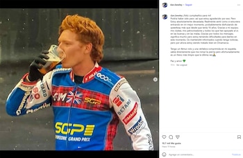 Dan Bewley, con cabello rojizo, bebe de un vaso de cerveza. Viste un uniforme de competición azul, rojo y blanco con parches de patrocinadores