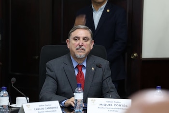 Hombre de traje y corbata roja sentado a una mesa con micrófonos y una botella de agua, un cartel lo identifica como Miquel Cortés