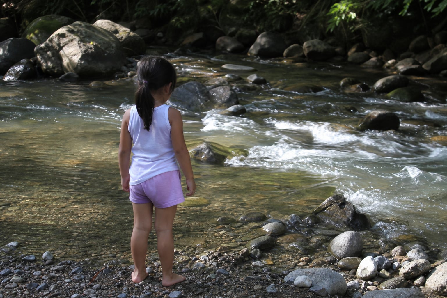 Una niña permanece descalza en la orilla de una quebrada mientras contempla la corriente de agua. (Imagen Ilustrativa Infobae)