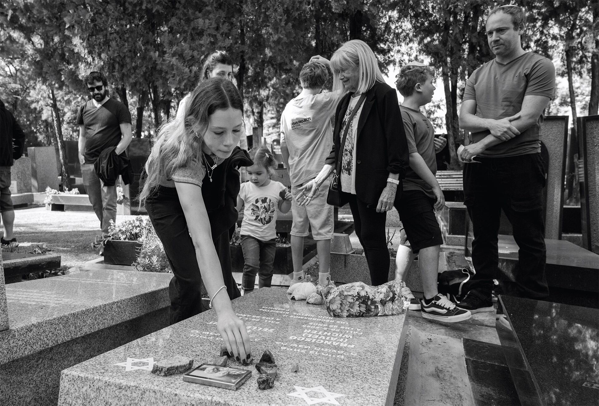 Es tradición judía poner piedras sobre la lápida de un ser querido en el cementerio. La costumbre indica que las piedras, a diferencia de las flores, no se marchitan y representan la permanencia del recuerdo del difunto. En esta foto, la bisnieta de Francisco se despide de sus bisabuelos alcanzando una piedra (2025)