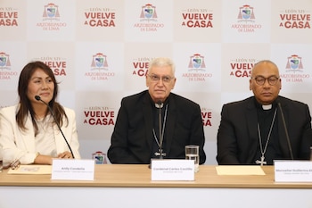 Tres personas sentadas tras una mesa con letreros de identificación frente a un panel con logotipos del Arzobispado de Lima