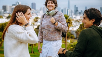 Un teléfono inteligente gris con un pequeño dispositivo rectangular rosado adherido a la parte trasera sobre un fondo blanco