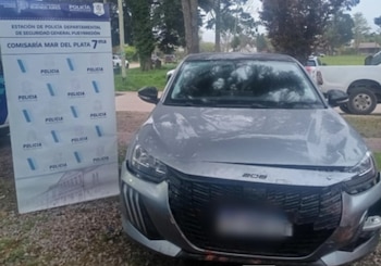 Un automóvil gris con el parachoques delantero dañado junto a un panel informativo de la Policía de la Provincia de Buenos Aires