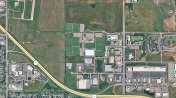 Vista aérea satelital con varias canchas de fútbol de césped, estacionamientos, edificios comerciales y una carretera que cruza el área