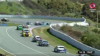Automóviles de carreras alineados avanzan sobre una curva de un circuito asfaltado bordeado por muros de protección y vegetación
