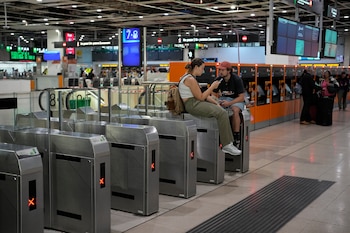 Dos pasajeros esperan la salida de su tren de Rodalies en la estación de Sants, en Barcelona, este domingo. (Alejandro García/EFE)