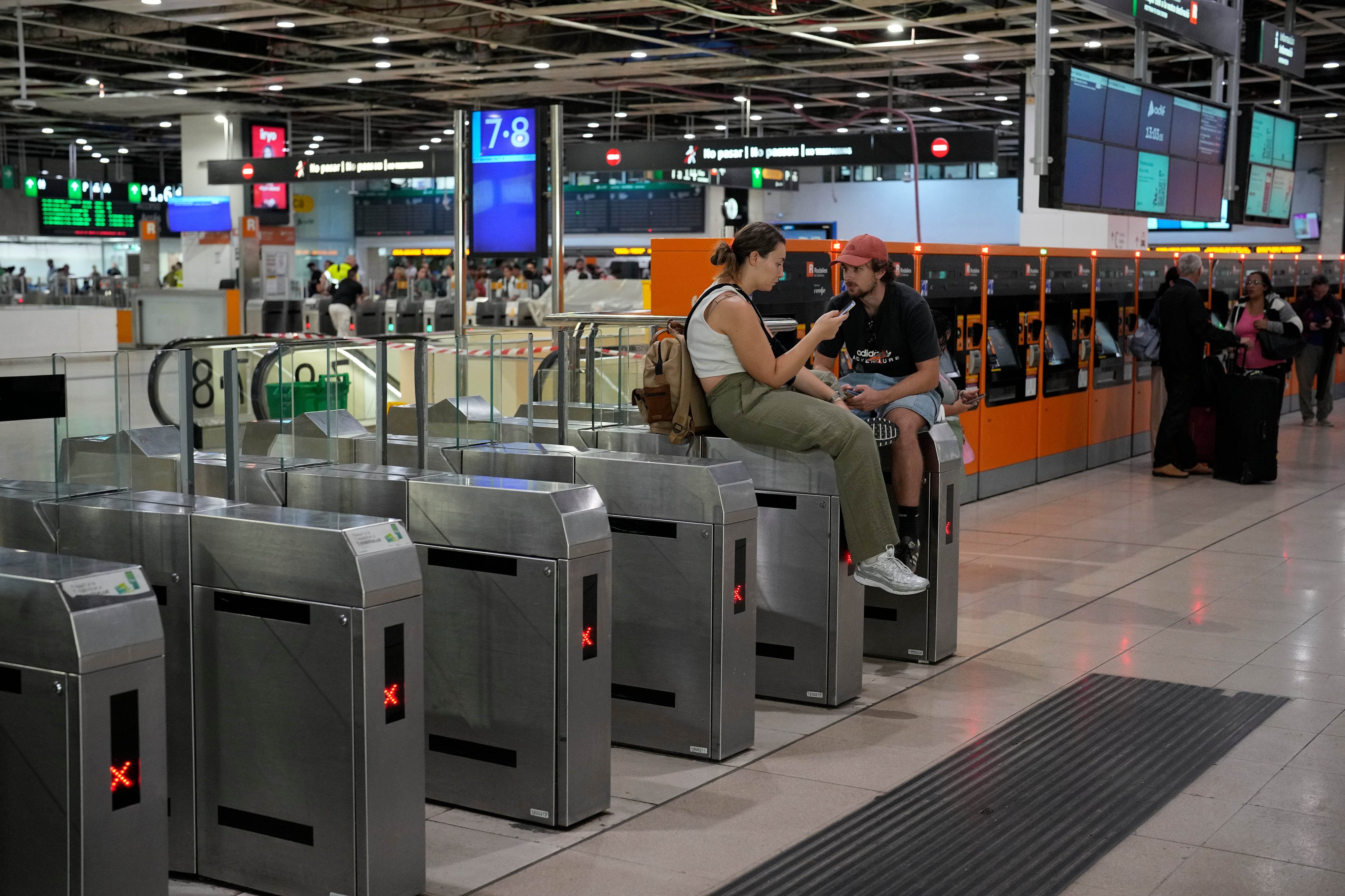 Dos pasajeros esperan la salida de su tren de Rodalies en la estación de Sants, en Barcelona, este domingo. (Alejandro García/EFE)