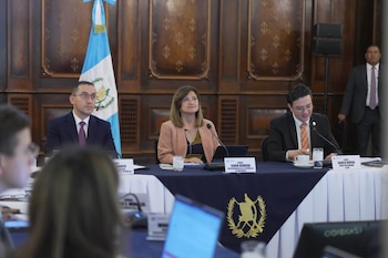 La vicepresidenta Karin Herrera y dos funcionarios permanecen sentados tras una mesa con la bandera de Guatemala al fondo