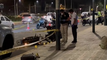 Dos agentes inspeccionan una motocicleta tendida en el asfalto, acordonada con cinta de seguridad amarilla y marcadores numéricos