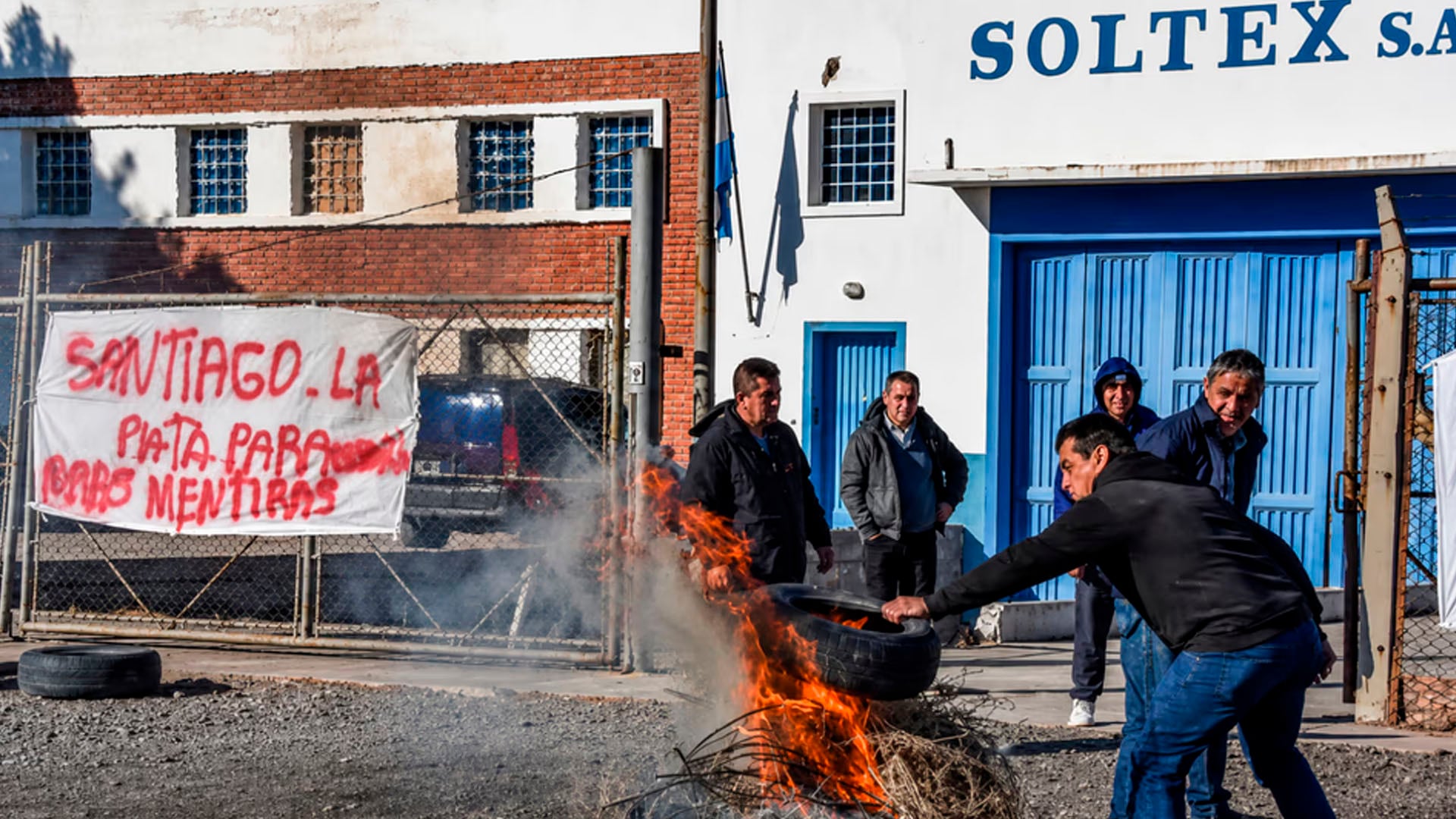 Trabajadores textiles de la empresa Soltex realizaron una protesta en Trelew, quemando neumáticos frente a la fábrica y exponiendo sus demandas laborales con pancartas. (NA)