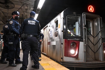 Miembros del NYPD patrullan el andén junto a un tren en servicio, reforzando la seguridad en estaciones de alta circulación.