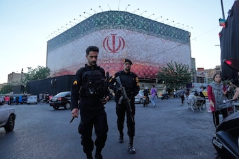 Policías caminan frente a una enorme pancarta con la bandera iraní en la plaza de la Revolución Islámica en Teherán, Irán, el domingo 14 de junio de 2026
(Foto AP/Vahid Salemi)