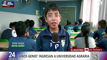 Niño con gafas y uniforme de Colegio Católico Juventud Científica habla a micrófono. Aula con estudiantes uniformados, pizarra, pupitres