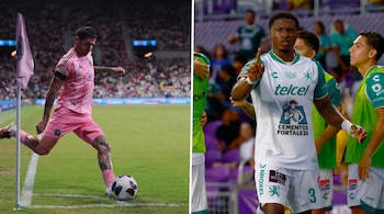 Dos futbolistas en el campo de juego. Uno de uniforme rosa patea un balón, el otro de uniforme blanco y verde apunta con el dedo.