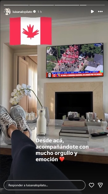 Primer plano de piernas con zapatillas blancas sobre una mesa de centro con libros y orquídea; al fondo, TV con desfile y bandera de Canadá