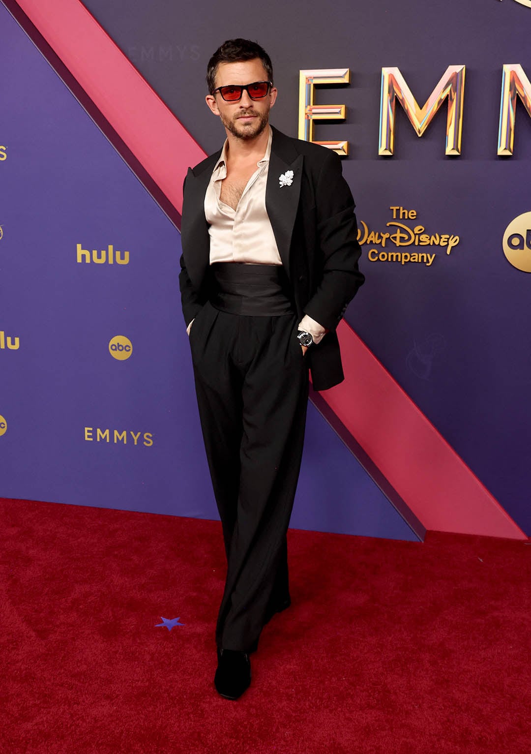 Jonathan Bailey incorpora una camisa satinada en gris perla a un traje negro de corte tradicional