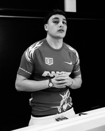 Fotografía en blanco y negro de un hombre joven con camiseta deportiva, reloj de pulsera y las manos entrelazadas