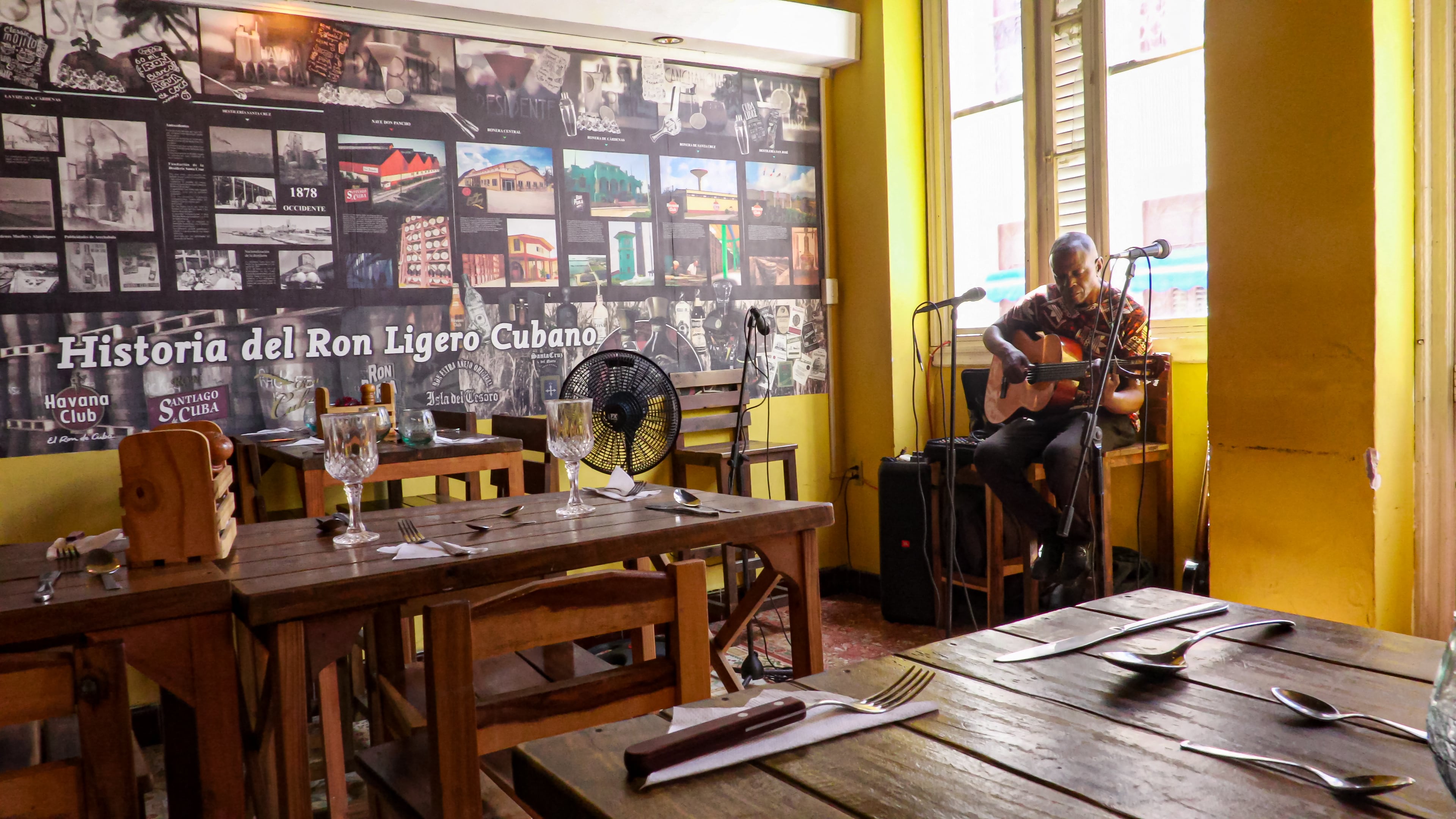 Un músico interpreta sus melodías entre mesas vacías que esperan clientes. (Infobae Cuba/ ADALBERTO ROQUE / AFP)