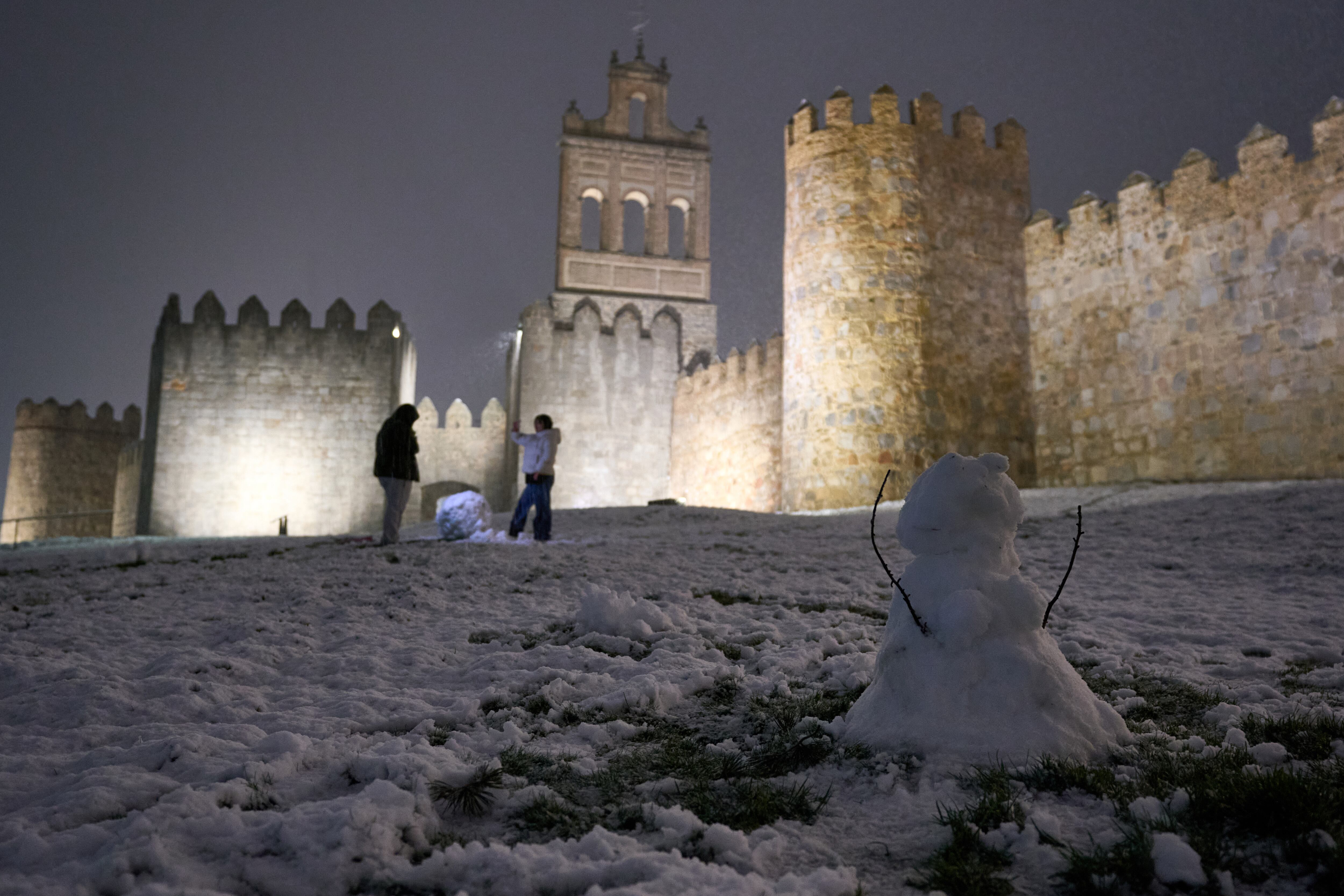 Varias personas juegan con la nieve tras las recientes precipitaciones caídas, este lunes en Ávila. (Raúl Sanchidrián/EFE)