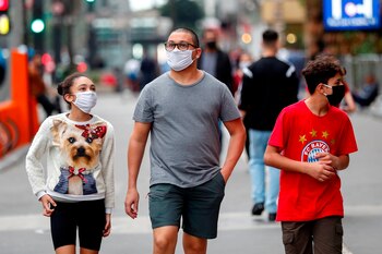 Personas con tapabocas caminan en