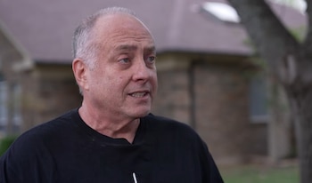 Un hombre caucásico de mediana edad, Jeff Metcalf, con cabello gris y una camiseta negra, mira con una expresión pensativa. Fondo borroso