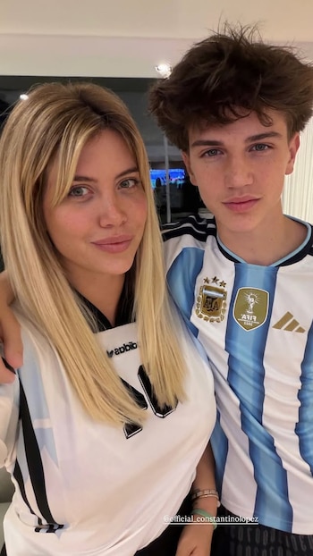 Wanda Nara y un joven, Constantino López, posan de cerca sonriendo. Ambos visten camisetas de fútbol de la selección argentina, con franjas celestes y blancas