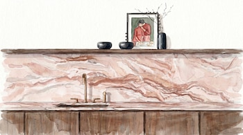 Ilustración de una cocina con encimera de mármol rosado, grifo dorado y gabinetes de madera. Un estante superior sostiene cuencos negros, un cuadro y un jarrón.