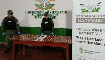 Dos gendarmes uniformados con chalecos GNA y guantes azules detrás de una mesa con numerosas cápsulas de cocaína y dos teléfonos celulares en Jujuy