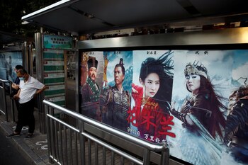 Público camina cerca de un anuncio que promociona la película de Disney "Mulán" en una parada de autobús en Beijing, China (Reuters)