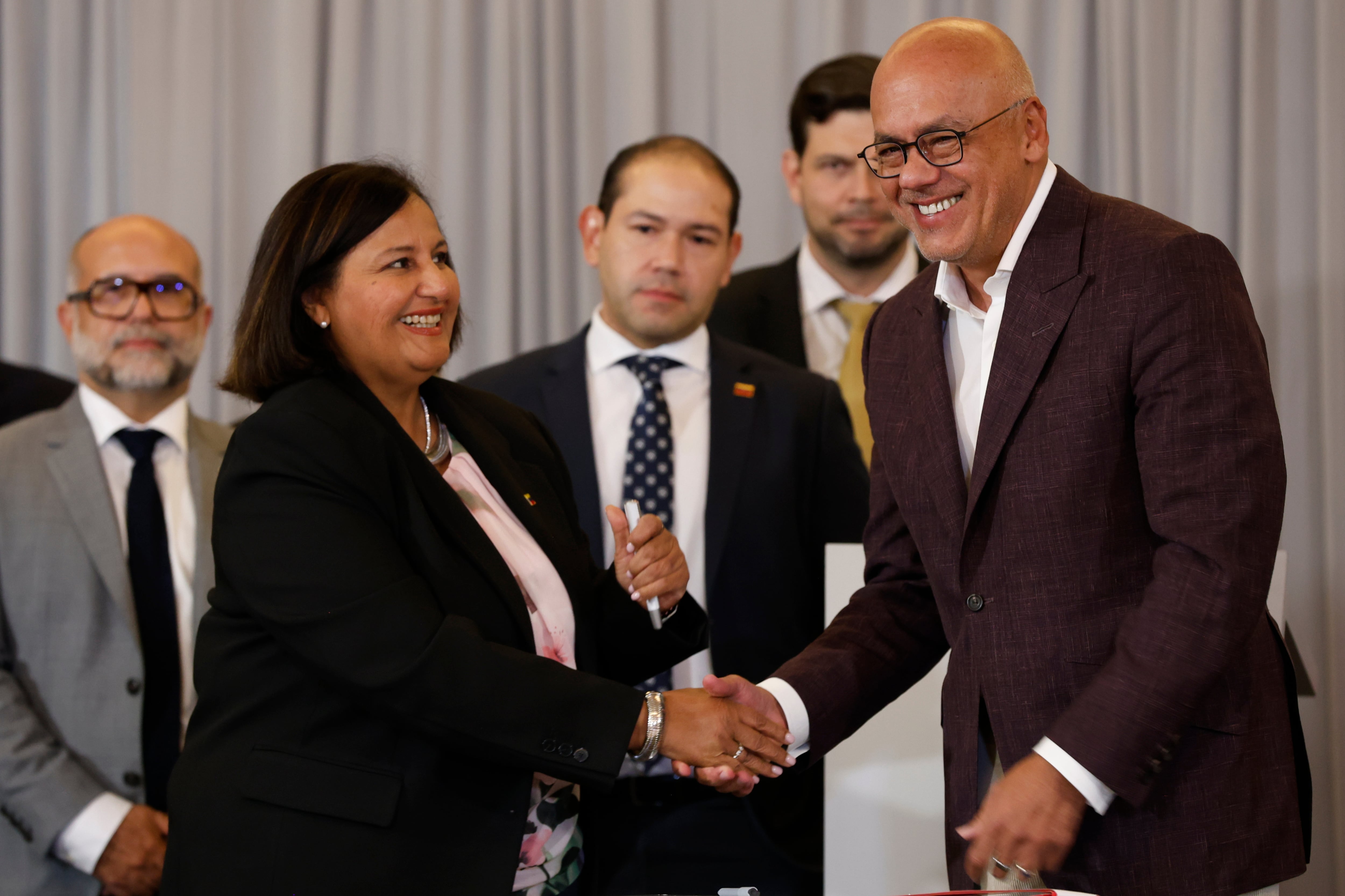 Dinorah Figuera, representante de la oposición venezolana, izquierda, y el presidente de la Asamblea Nacional, Jorge Rodríguez, se estrechan la mano tras firmar acuerdos al finalizar la segunda ronda de conversaciones políticas, el viernes 25 de septiembre de 2026, en Caracas, Venezuela. (AP Foto/Pedro Mattey)