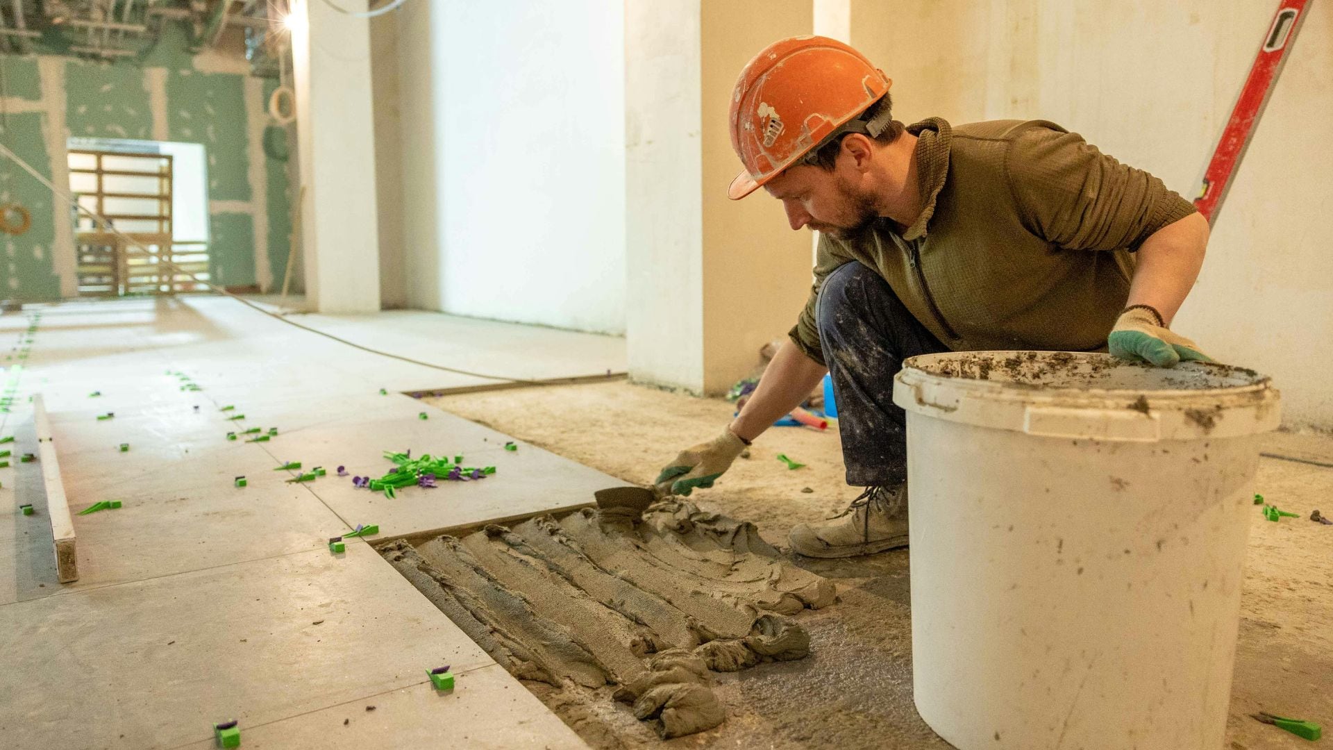 Un albañil reforma el suelo de una vivienda (Canva)