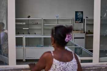 Una imagen de Fidel Castro cuelga en la pared de una farmacia estatal donde una mujer solicita medicamentos en La Habana, Cuba, el miércoles 29 de julio de 2026 (AP/Ramon Espinosa)