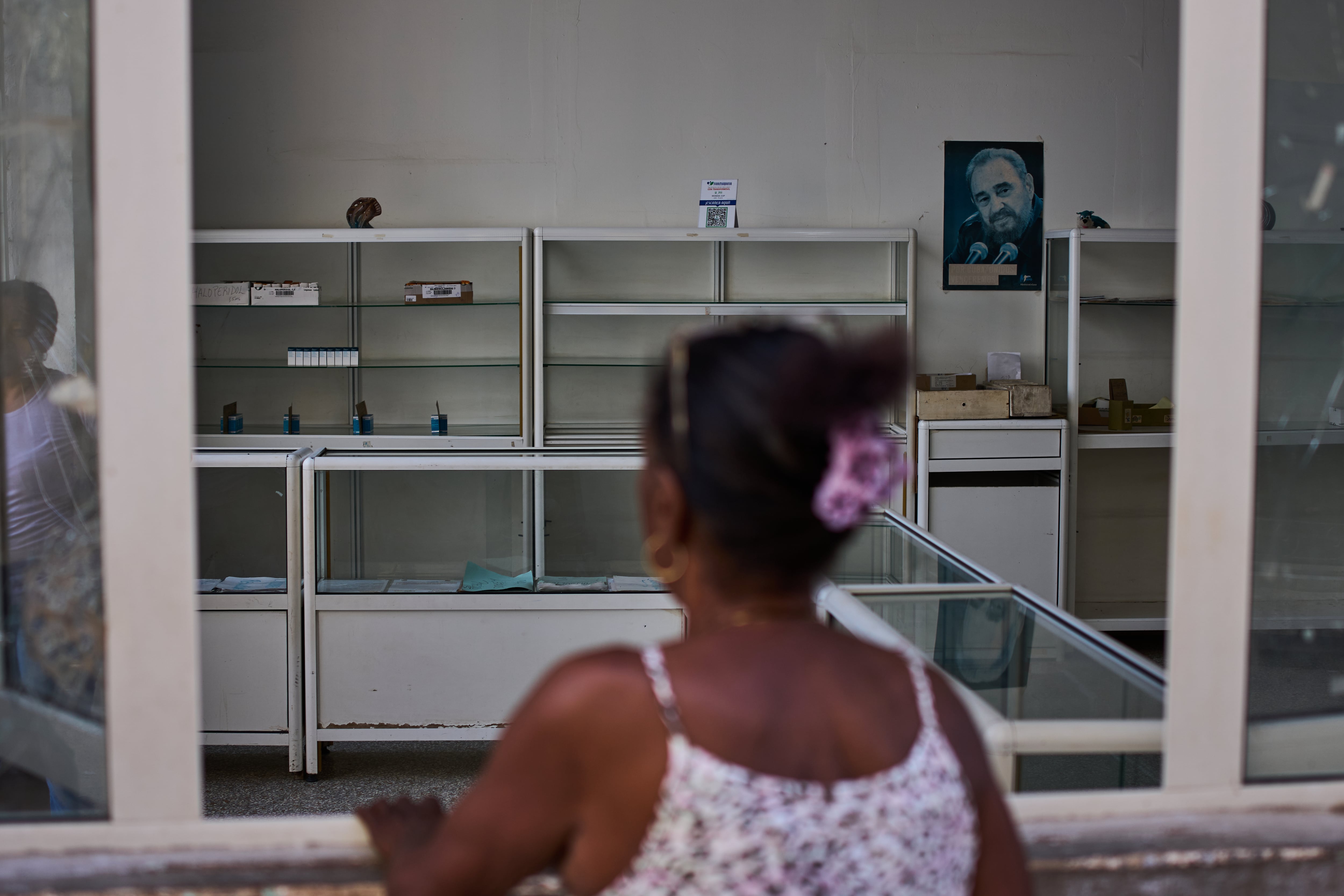 Una imagen de Fidel Castro cuelga en la pared de una farmacia estatal donde una mujer solicita medicamentos en La Habana, Cuba, el miércoles 29 de julio de 2026 (AP/Ramon Espinosa)