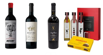 Tres botellas de vino tinto, tres frascos de aderezo, una caja de alfajores Havanna y una caja roja de chimichurri sobre un fondo blanco