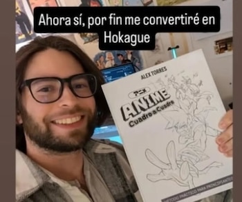 Um homem com barba, óculos e cabelos longos sorrindo segurando um livro branco de anime. O texto que acompanha dizia: 'Agora me tornarei Hokague'